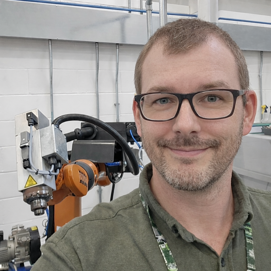 Adam Morgan in front of a KUKA robot arm